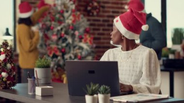 Mevsimsel süslemeler ve dekorasyonlarla ofiste beyin fırtınası yapan çeşitli meslekdaşlar. Çalışanlar noel tatilinde bilgisayardaki verilerle takım çalışması yapıyorlar..