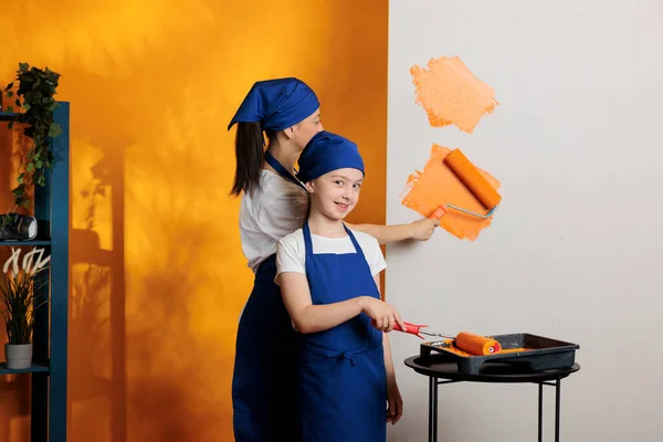 아이가 어머니와 그리는 오렌지 페인트와 브러시를 사용하여 아파트 작업을 내부를 — 스톡 사진