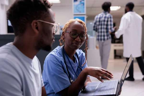 Kvinnlig Sjuksköterska Använder Bärbar Dator Med Patienten Konsultation Väntrummet Visar — Stockfoto