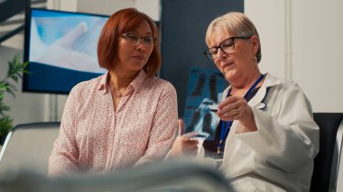 Radyografi araştırması yapan yaşlı hasta ve doktor hastalığa karşı sağIık tedavisi buldu. Kontrol ziyareti sırasında kemiklerin röntgen taraması teşhisi inceleniyor. El kamerasıyla..