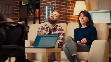 Evlilik ve ofisteki ilişki hakkında konuşmak için danışmanla çift terapisi seansına katılan insanlar. Kadın ve erkek terapistle görüşmede psikanaliz yapıyorlar. El kamerasıyla..