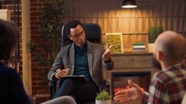 Evlilik danışmanı psikoloji ofisinde psikoterapi seansına katılıyor, ilişki sorunları olan insanları dinliyor. Erkek terapist toplantıda psikanaliz yapıyor..