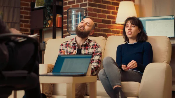 Evlilik ve ofisteki ilişki hakkında konuşmak için danışmanla çift terapisi seansına katılan insanlar. Kadın ve erkek terapistle görüşmede psikanaliz yapıyorlar. El kamerasıyla..