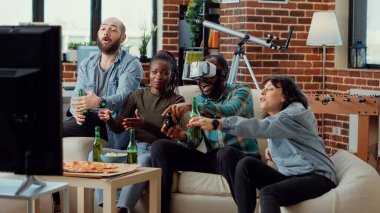 Çeşitli insanlar video oyunları oynamak için VR gözlükleri kullanıyor, TV konsolunda online oyun yarışmasıyla eğleniyorlar. Televizyonda sanal gerçeklik kulaklıklarıyla meydan okumak, takılmaktan hoşlanmak..