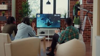 Neşeli arkadaşlar konsolda online oyun kazanmayı kutluyor, video oyunu oynuyor ve kazanıyor. İnsanlar yarışmadan zevk almak ve eğlenmek için oyun oynamak konusunda mutlu..