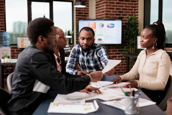 Startup employees doing teamwork to plan project, analyzing information and data on documents. Using laptop and paperwork files to do research and create corporate presentation in office.