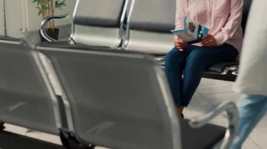 Hemşire, Asyalı kadına sigorta desteğini açıklarken lobide oturmuş, sağlık kontrolüne hazırlanıyor. Sağlık merkezinde tıp ve tedaviden bahsediyoruz..