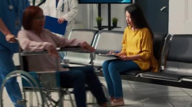 Kıdemli doktor ve Asyalı kadın sağlık kliniğinde konsültasyon yapıyorlar, hastalık teşhisi ve tedavisi hakkında konuşuyorlar. Tesis lobisinde check-up randevusu, tıbbi danışmanlık.