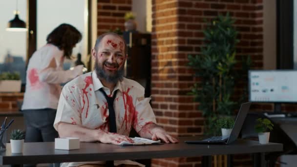 Bezmyślne Przerażające Zombie Uśmiechające Się Kamery Siedząc Przy Biurku Straszny — Wideo stockowe
