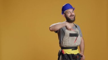 Stüdyoda baş parmağını gösteren bir zanaatkârın portresi onay ve uzlaşmayı ifade ediyor. Kendine güvenmek ve olumlu davranmak işaret gibi, memnuniyet ve başarı hakkında neşeli olmak..