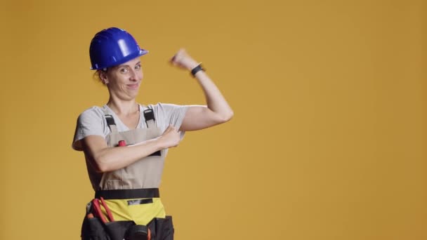 强大的女权运动者在工作室中弯曲手臂肌肉 准备用工具整修建筑 有自信的大手女子指着二头肌和三头肌 — 图库视频影像