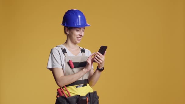 インターネットを閲覧し 改装のインスピレーションを見つけるためにスマートフォンを使用して女性エンジニアの肖像画 解体作業によって権限を与えられる非典型的な仕事感覚を持つ自信者 — ストック動画