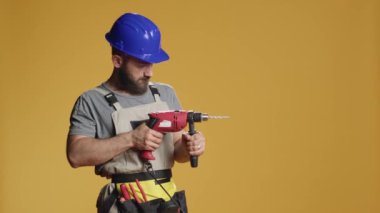 Tamirci müteahhit çivileri elektrikli matkapla deliyor inşaat inşaatında vida makinesiyle çalışıyor. Çivi tabancası kullanıyor ve tadilat için önlük takıyor..