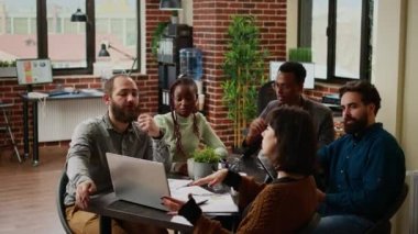 Diverse team of coworkers analyzing research data on laptop, planning business report and charts presentation in boardroom meeting. Doing teamwork to create partnership project.