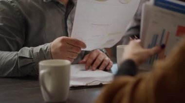 Business people analyzing research information on documents, looking at papers with rate charts and graphs. Office employees working with infographics report and review. Close up.