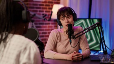 Selective focus on online radio host doing high five hand gesture with african american singer during live podcast in home studio. Portrait of influencer with headphones high fiving while recording