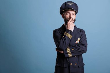 Üniformalı sorgulayan, karar veren, düşünen, karar veren dalgın bir havayolu pilotu. Yüzünde belirsiz yüz ifadesi olan düşünceli bir yüzbaşı.