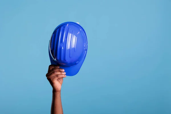 スタジオでハードハットを被った建設労働者が青を背景に撮影した 作業保護のカメラオブジェクトの前に表示される認識できない人 建設安全コンセプト — ストック写真