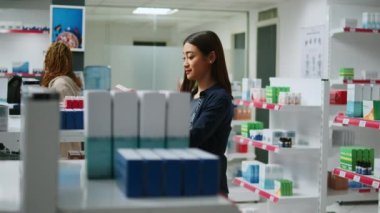 Mutlu Asyalı müşteri raflardaki ilaç paketlerini kontrol ediyor, eczaneden almak için sağlık ürünlerine bakıyor. Eczanede, eczanede kardiyoloji hapı okuyan kadın..