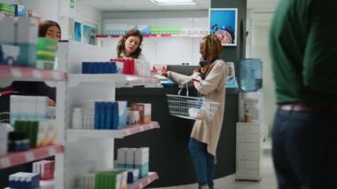 Kadın müşteri reçeteli tedavi satın almak için eczane raflarından kutu kutu ilaç alıyor, ilaç ve ilaç paketleri alıyor. Eczacıya vitamin ve uyuşturucuyu soruyorlar..