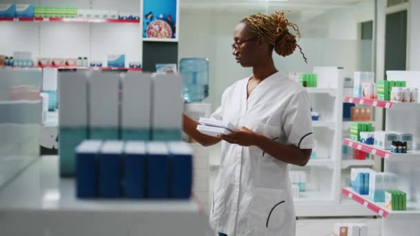 薬局の棚で薬の箱を分析する女性薬剤師の笑顔 顧客を助けるためにビタミンや薬瓶を見て 医薬品を扱うドラッグストアで働く従業員 — ストック動画