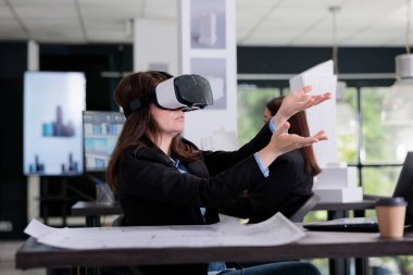 VR kulaklık takan mimar metaverse tasarım yapıyor, sanal yapı modeline dokunuyor, proje üzerinde çalışıyor. Mimarlık bürosunda çalışan mühendis, AR gözlükleri takan emlakçı.