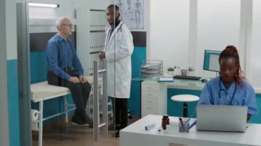 Pratisyen hekim ilaç ve ilaç veriyor, yaşlı bir adama hastalık konusunda danışıyor. Hekim, hastaya reçeteli tedavi, ilaç ve antibiyotik tedavisi için yardım ediyor..