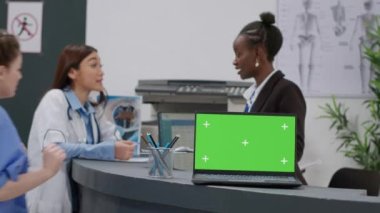 Resepsiyondaki laptopta yeşil ekran ile çalışan çeşitli tıbbi ekipler. İzole edilmiş telif alanı arka planı, boş model şablonu ve ekranda krom tuş görüntüsü kullanan bilgisayar.