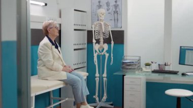 Üst düzey kadın, kabinede doktorla tıbbi istişareye katılmak için bekliyor. Uzman doktorla sağlık kontrolünde randevusu var. Ofiste oturan hasta, sağlık desteği..