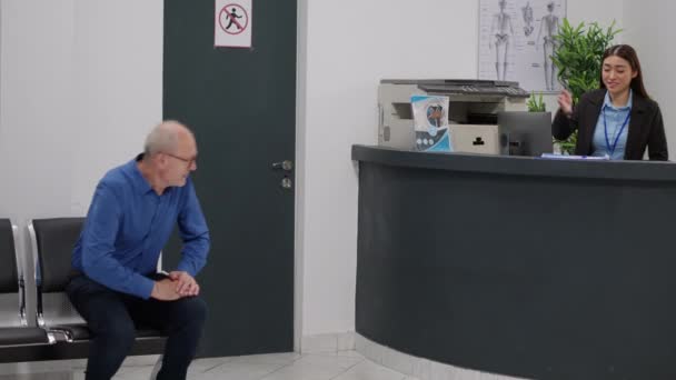 Empfangsdame Hilft Alten Patienten Beim Ausfüllen Von Krankenakten Hat Eine — Stockvideo