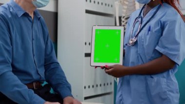 Medical nurse and old man looking at greenscreen display on digital tablet, with face masks. Analyzing chromakey display with isolated mockup template and copyspace background. Close up.