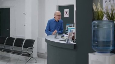 Hasta, tıp merkezindeki doktorla randevuya gitmeden önce kadın resepsiyonistle konuşuyor. Hastane resepsiyonunda yaşlı adama sağlık raporları için yardım eden bir kadın..