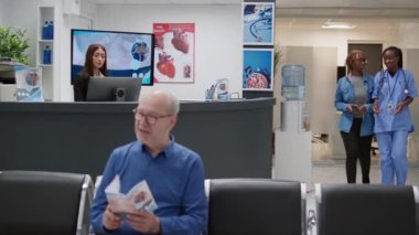 Klinik resepsiyonunda kredi kartıyla sağlık muayenesi yapan genç bir yetişkin uzman ile randevusu var. Hasta lobideki resepsiyonistle konuşuyor..