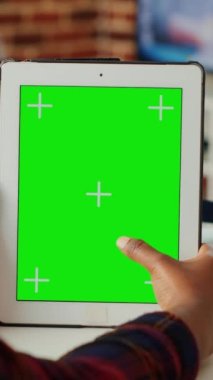 Dikey video: Genç öğrenci dijital tablet üzerinde yeşil ekran şablonu kullanıyor, cihazdaki izole edilmiş telif alanı görüntüsünü analiz ediyor. Boş krom anahtar modeli ve taşınabilir kablosuz cihazla çalışıyor. Kapat..
