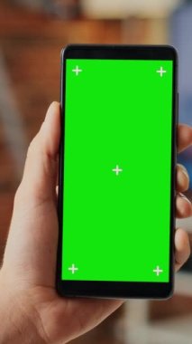 Dikey video: Cep telefonunda yeşil ekran şablonuyla çalışan ofis çalışanı, boş arkaplan ve krom tuş ekranıyla akıllı telefon kullanıyor. İzole edilmiş fotokopi alanına bakıyorum. Kapat..