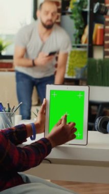 Dikey video: Genç öğrenci yeşil ekran şablonu ile dijital aygıtı analiz ediyor, tablet ekranda krom anahtar ekran ile çalışıyor. İzole edilmiş kopyalama alanına ve boş model arkaplana bakılıyor