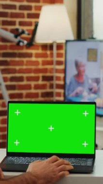 Dikey video: Modern yönetici taşınabilir bilgisayarda yeşil ekran ekranlı dizüstü bilgisayara bakıyor ve boş krom anahtar şablonunu analiz ediyor. İzole edilmiş arkaplan ve pc üzerindeki kopyalama alanı denetleniyor.