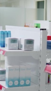 Dikey video: Asyalı eczacı, tedavi ve ilaç hastalarına yardımcı olmak için eczane raflarındaki destek kutularını analiz ediyor. Eczacılara bakıyor, notlar alıyor, eczanede çalışıyor..