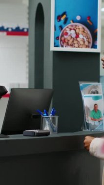 Dikey video: Afrikalı Amerikalı bir kadın eczane tezgahında ilaç almak için kredi kartıyla ilaç ödüyor. Müşteri temas kurmadan ödeme yapıyor ve ilaç alıyor..