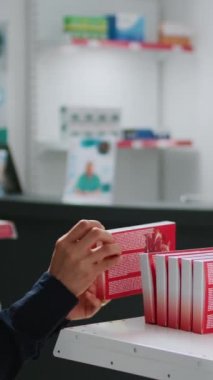 Dikey video: Eczane tezgahından sağlık ilacı almak için kutuda kardiyoloji hapları tutan Asyalı bir müşteri, eczacıyla destek ve tedavi hakkında konuşuyor. Uyuşturucu ve eczacılara bakıyorum.