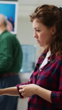 Dikey video: Eczane perakende mağazasında ilaç ve vitamin içeren rafları inceleyen kadın müşteri, ilaç almak için ilave paketlere bakıyor. İlaç ürünleri ve haplar kontrol ediliyor