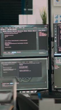 Dikey video: Uçbirim penceresinde çoklu ekran geliştirme yazılımı olan boş ofis masası, kod veritabanı algoritmalarını, ağ sunucularının yeniliklerini gösteren ajans bilgisayarları.