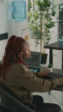 Dikey video: Afrikalı Amerikalı programcı yeni kullanıcı arayüzü oluşturmak için bilgisayara kaynak kod yazıyor. Uçbirim penceresinde güvenlik sunucusu geliştirmek için html dilinde veri yazan yazılım mühendisi.