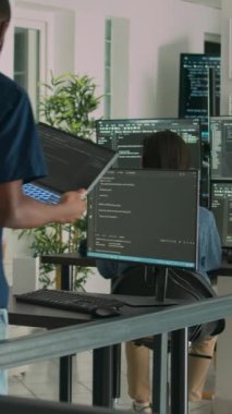 Dikey video: Bilgisayarda kod yazmak ve sistem bilgilerini görüntülemek için dizüstü bilgisayar kullanan Afrikalı Amerikalı geliştirici. Yazılım ajansındaki kullanıcı arayüzü üzerinde çalışan veritabanı kodlayıcı ayrıştırma algoritması.