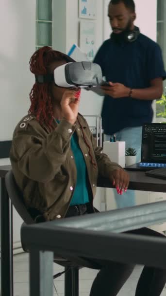 垂直ビデオ アフリカ系アメリカ人のプログラマーは 仮想現実ヘッドセットを使用してセキュリティプログラムを開発し 開発オフィスでVrメガネで作業しています ビッグデータ管理者がデータベースとHtmlスクリプトをコーディング — ストック動画