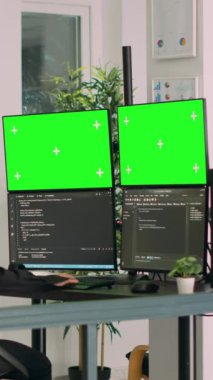 Dikey video: Yazılım yenilik ofisindeki çoklu monitörlerde html betik kodu ve yeşil ekran kullanan Asyalı sistem mühendisi. Uçbirim penceresi ve izole edilmiş kromakey ekran ile çalışan programcı