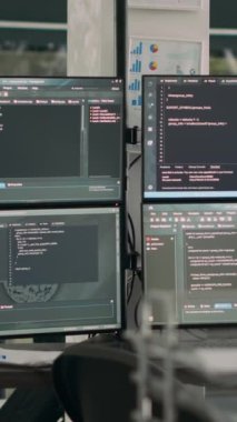 Dikey video: Boş ofis masasında veri algoritmaları derleyen bilgisayarlarla ayrıştırma kodlarını gösteren monitörler. Temrinal üzerine html betiği olan yapay zeka sunucuları bulut hesaplama