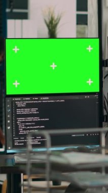 Dikey video: Terminal penceredeki yeşil ekran ve koda bakan kadın programcı, ofisinde kromakey ekran ve html betiği ile çalışıyor. Yazılım geliştirme üzerinde izole edilmiş kopyalama alanı kullanılıyor