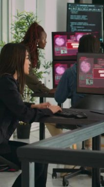 Dikey video: Sistem mühendislerinden oluşan bir ekip web sunucusunu hackleyerek, ofisteki birden fazla monitördeki kritik hatayı okuyor. Çeşitli yazılım geliştiricileri hackleme sorununu çözmeye çalışıyor, güvenlik duvarı güvenliği