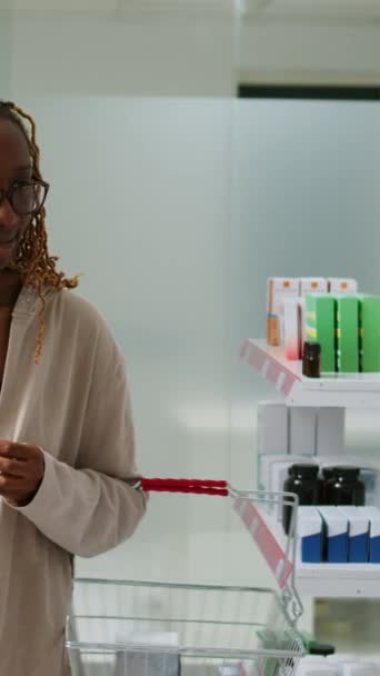 Pionowe Wideo Afrykański Amerykański Klient Analizuje Produkty Farmaceutyczne Półkach Apteki — Wideo stockowe